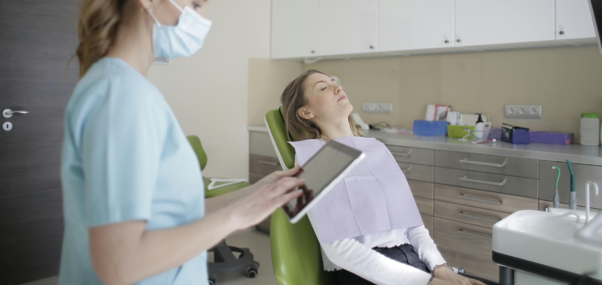 Female orthodontist using tablet while assisting patient in clinic